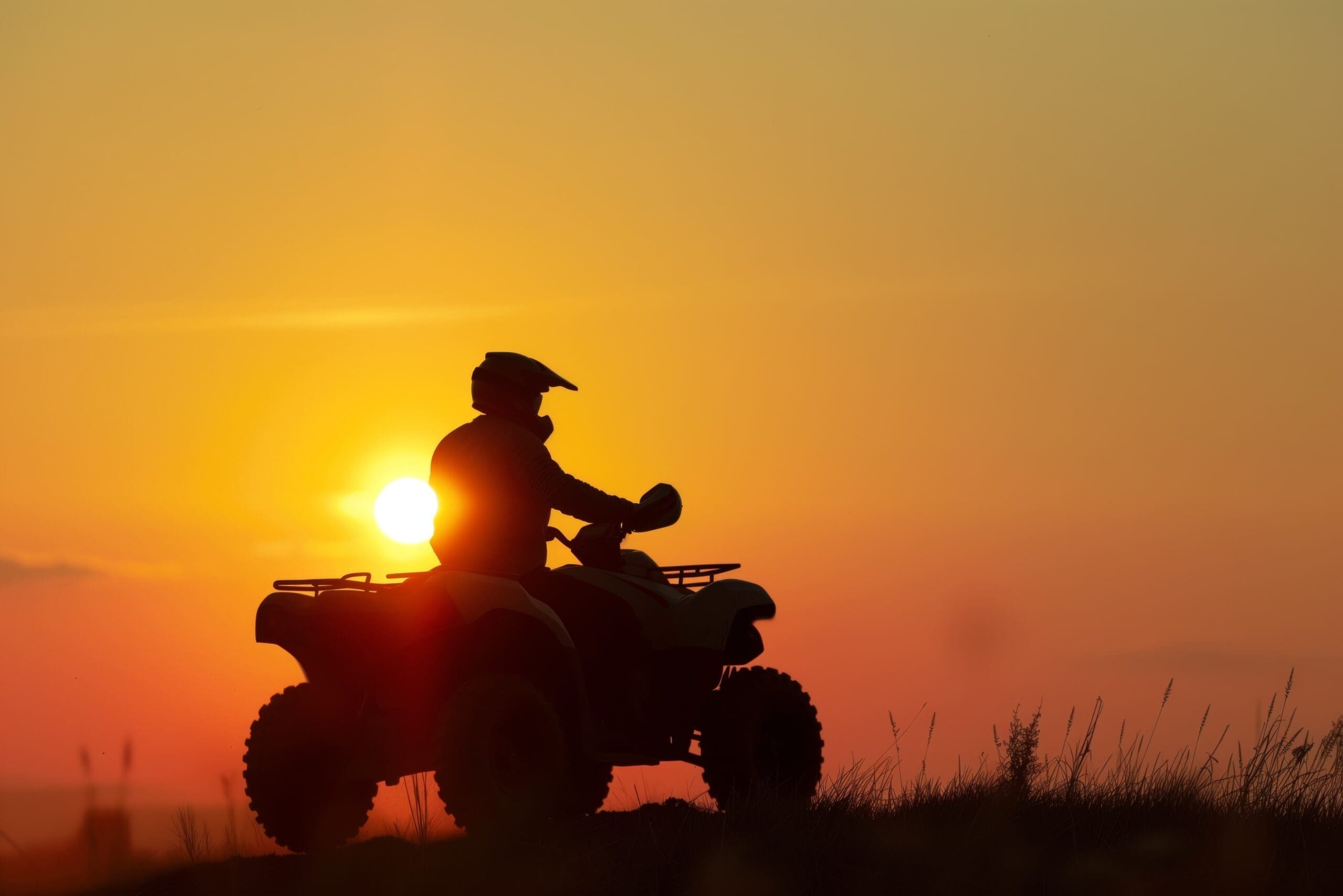 silhouette of an atv rider against a setting sun